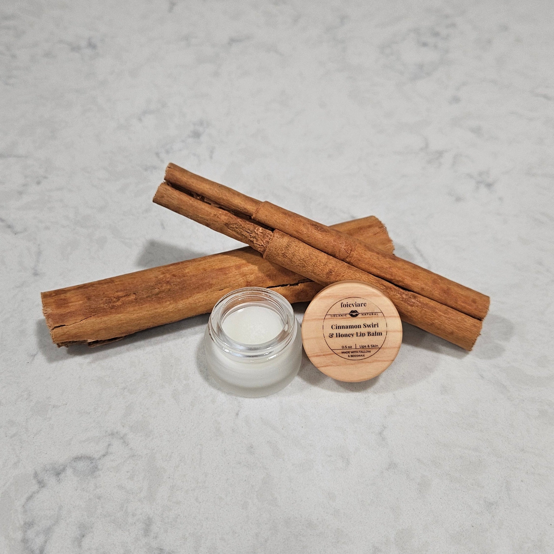 Cinnamon sticks and a small glass container on a marble surface